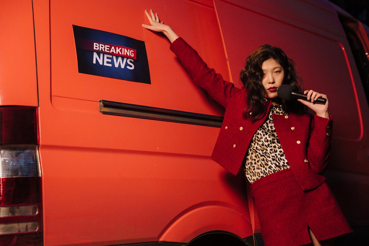 Fashionable reporter with microphone posing dramatically next to a news van.
