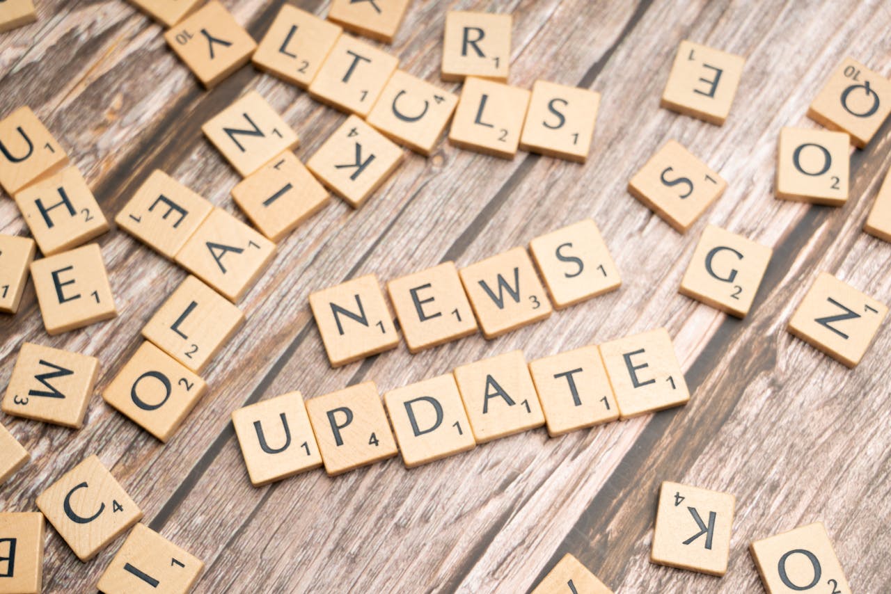 Scrabble tiles spelling 'News Update' on a wooden background, ideal for media and communication concepts.